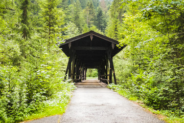 wooden covered bridge crossing a river surrounded by forest