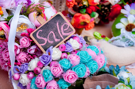 Inscription sale on board among artificial flowers