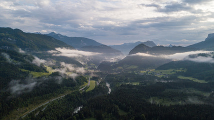 Aerial view of the morning foggy landscape in the alpine mountains with road