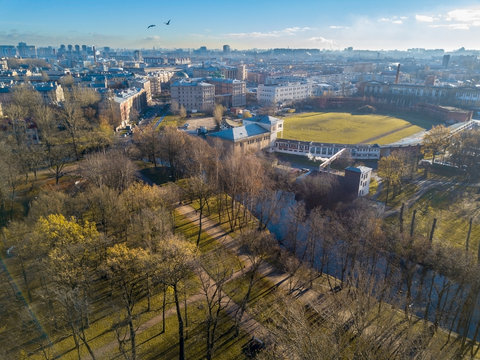 Panoramic view of city with recreation area and sports facilitys; autumn morning with long trees shadows and blue channel; urban city life on the background; Saint Petersburg, Russia