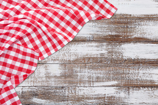 Vintage wooden table with red checkered tablecloth. Top view mockup.