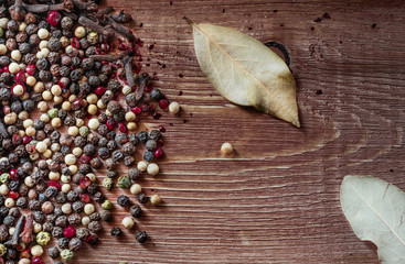 Mix of peppercorns on rustic background. Red, black, green and white dry pepper in seeds.