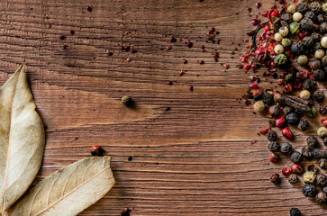 Mix of peppercorns on rustic background. Red, black, green and white dry pepper in seeds.