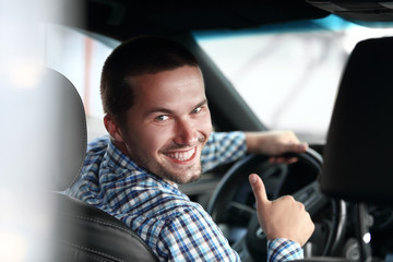 modern man sitting in a car and showing his thumb up.