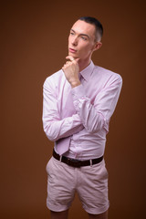 Young handsome androgynous businessman against brown background