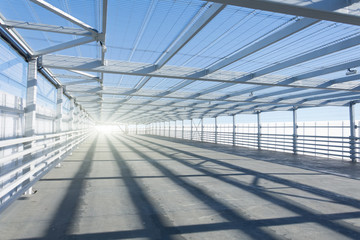 Metal tunnel grating with bright light at the end.