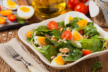 Delicious salad of fresh spinach, boiled egg, tomatoes, nuts and sunflower seeds