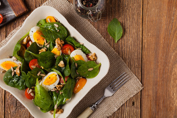 Delicious salad of fresh spinach, boiled egg, tomatoes, nuts and sunflower seeds