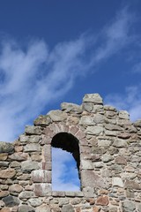 Window opening in olde stone wall against blue sky