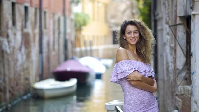 Travel tourist woman standing on the pier against beautiful view on venetian chanal with boats in Venice, Italy. Attractive young romantic girl on vacation walking happy by Grand Canal.