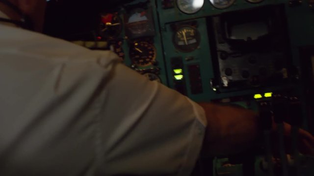 Handheld shot of unrecognizable male aircraft captain sitting in cockpit and controlling plane