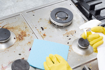Cleaning a gas stove with kitchen utensils, household concepts, or hygiene and cleaning.