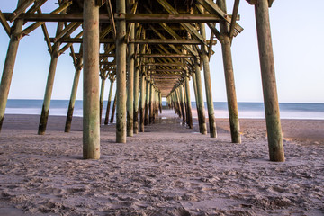 Myrtle Beach South Carolina. Looking under a long wooden pier along the wide sandy beaches of the Grand Strand on the Atlantic Ocean coast of South Carolina.