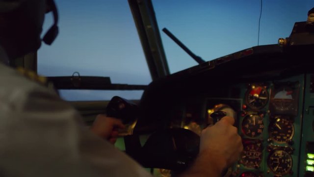 PAN shot of unrecognizable male aircraft captain sitting in cockpit and piloting airplane