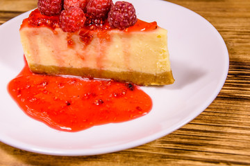 White plate with cheesecake New York and raspberries on wooden table