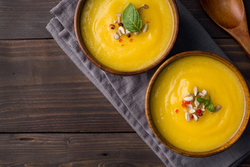 Pumpkin soup mashed with spices in wooden bowls on dark boards.