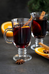 Red mulled wine in glass with spices at dark background