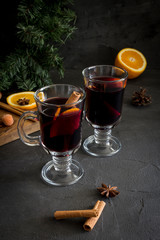 Red mulled wine in glass with spices at dark background