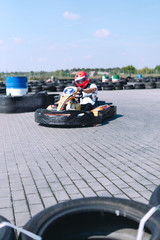Go-Kart racing car on the track in action, championship, active sports, extreme fun, the driver keeps his hands on the wheel. driver protective gear. day. selective focus, vertical photo, karting