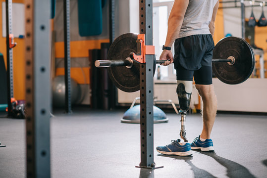 cropped shot of athletic sportsman with artificial leg working out with barbell at gym - Powered by Adobe