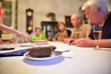 Delicious homemade nut cake dessert with almonds on top on a table with blurred people around it.