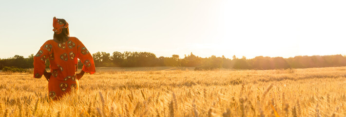African woman in traditional clothes standing in a field of crops at sunset or sunrise