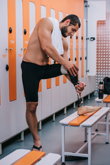 Fototapeta premium smiling young sportsman with artificial leg standing at changing room of swimming pool