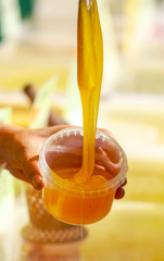 Beekeeper pours honey into the container on the market