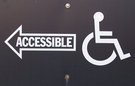 Handicapped Accessible Sign. Black sign with white writing and arrow pointing handicapped accessible entrance. 