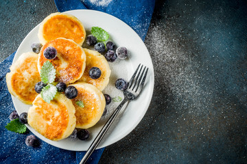 Homemade cheese pancakes with fresh berries and honey, dark background copy space