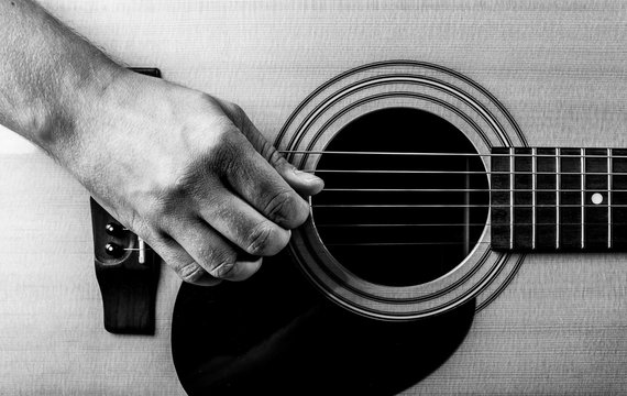 old man's hand on the strings of an acoustic guitar. close-up