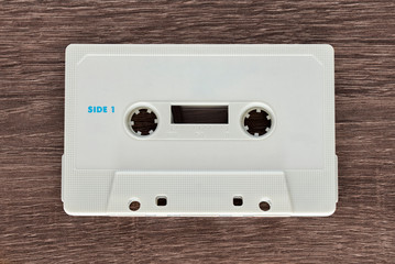 Obraz premium Vintage white audio cassette tape on brown wooden background. Side 1