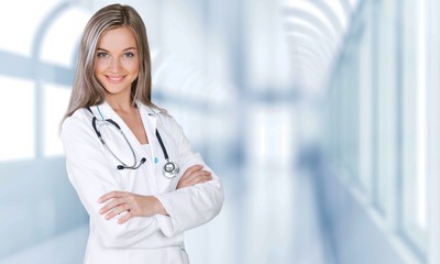 Attractive young female doctor with blurred hospital interior on
