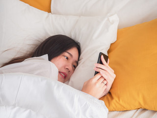 asian girl wake up on bed and playing with the mobile phone