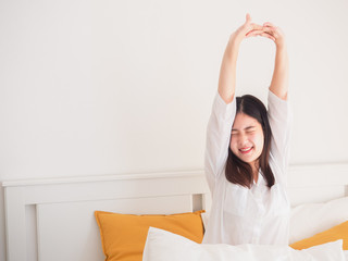 asian woman stretching in bed after wake up
