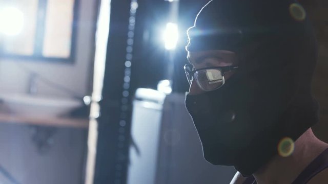 Masked person sitting near laptop, breaking government server. Security concept. Anonymous hacker, genius, cyber attack, insecurity.