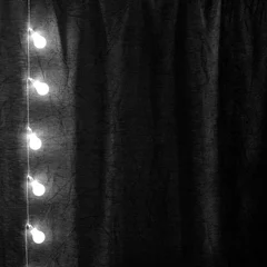 Papier Peint photo Lumière et ombre Garland of light bulbs hanging verticaly in the dark room