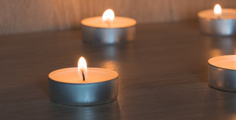 Burning candles. Small round tea light candles on wooden table front view.