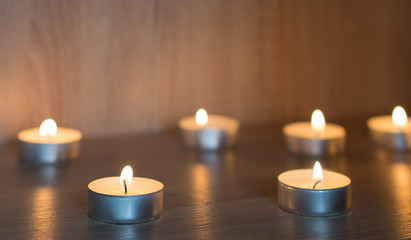 Burning candles. Small round tea light candles on wooden table front view.