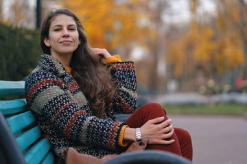Pretty young woman sitting on a bench enjoying the good weather.