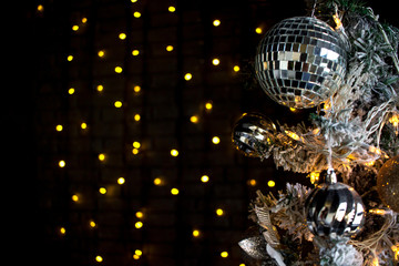 Fototapeta na wymiar Christmas toys on a pine tree. Shiny ball, orange light bulbs and balls. Dark background.