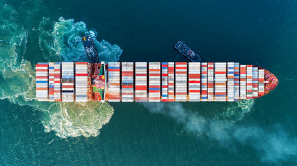 Aerial view Tug boats drag container ship with beautiful wave to sea port for unloading container for import  export or transportation concept background.