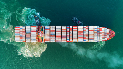 Aerial view Tug boats drag container ship with beautiful wave to sea port for unloading container...