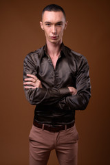 Fototapeta premium Young handsome androgynous businessman against brown background