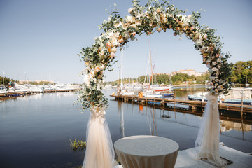 Fototapeta premium Arch decorated with flowers for the wedding ceremony in the yacht club