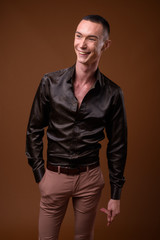 Fototapeta premium Young handsome androgynous businessman against brown background