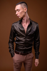 Fototapeta premium Young handsome androgynous businessman against brown background