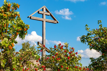 The Orthodox cross against the sky , in the bushes of mountain ash