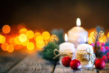 Merry Christmas and happy New year. Candle and Christmas toys on a wooden table on the background of a garland. Bokeh. Selective focus. Background with copy space.