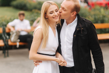 Handsome man kiss her lovely wife. Beautiful woman in white dress hug his husband